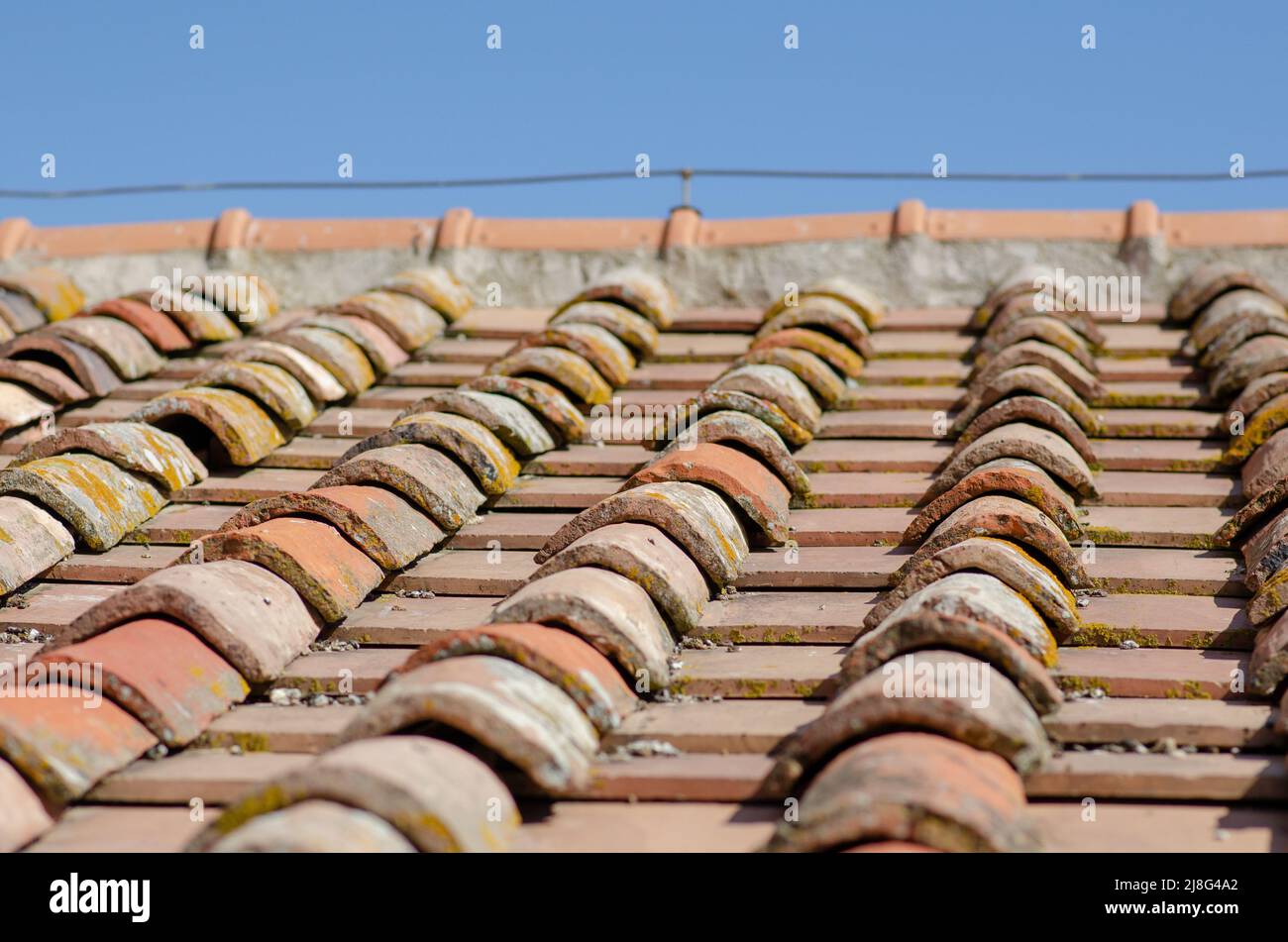 House: pitched roofs with brick tiles, exposed upper ridge and ridge tiles. The shingles are clay or terra cotta, an ancient design of curved. Stock Photo