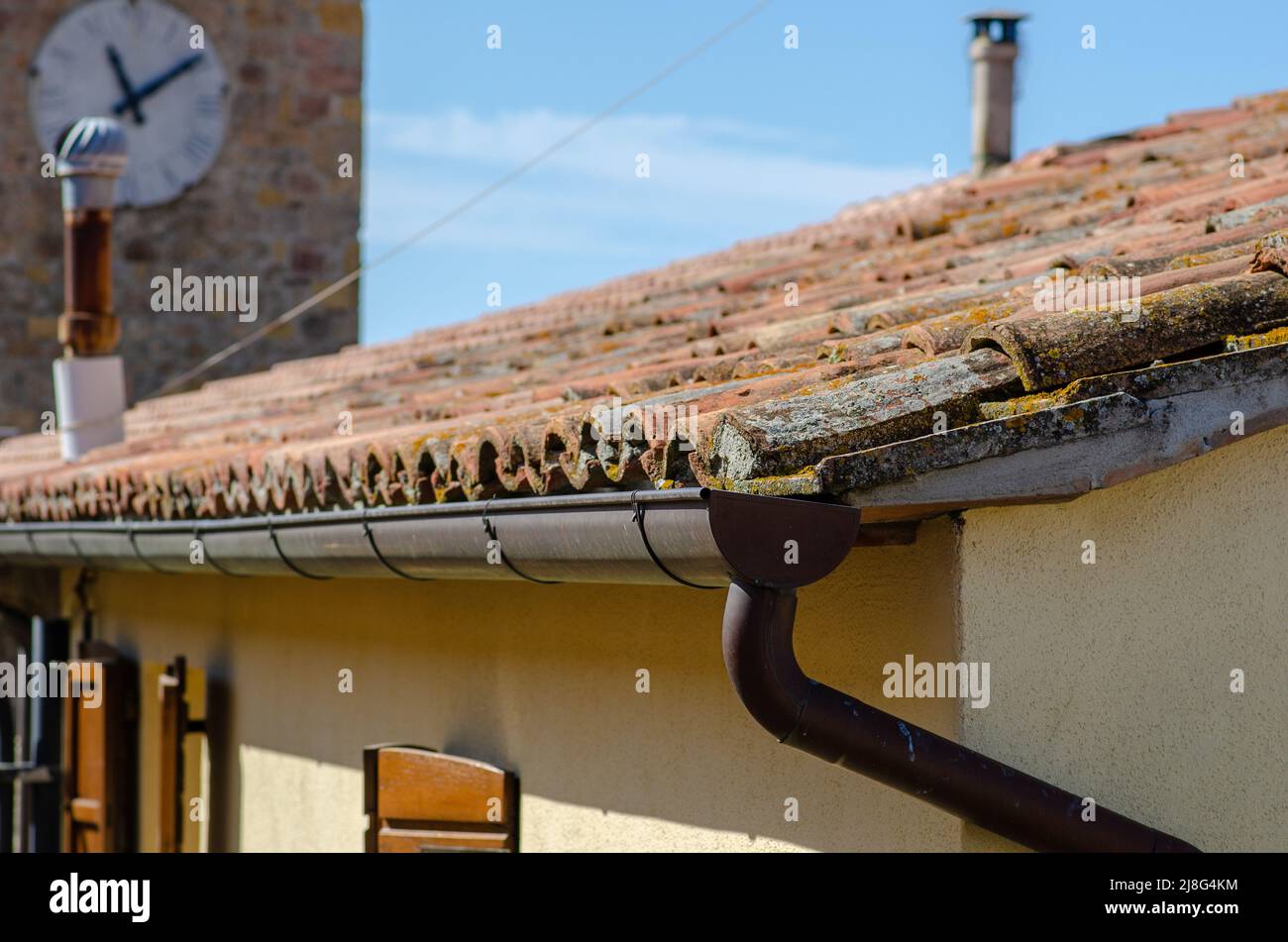 House: building with pitched roof with brick tiles, visible the wool eaves, and front of the cornice. Stock Photo