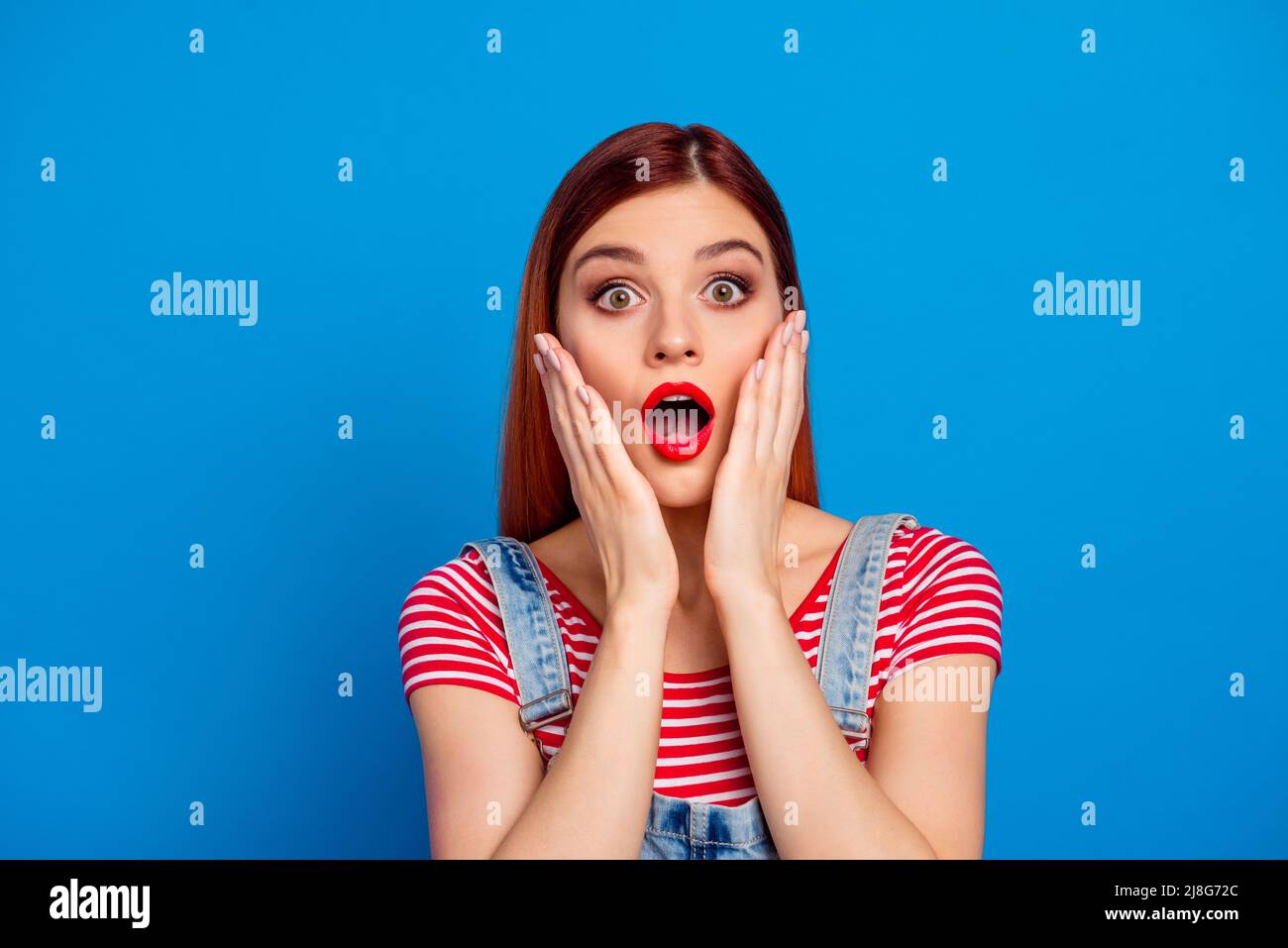 Photo of charming impressed young lady dressed red clothes arms cheeks ...