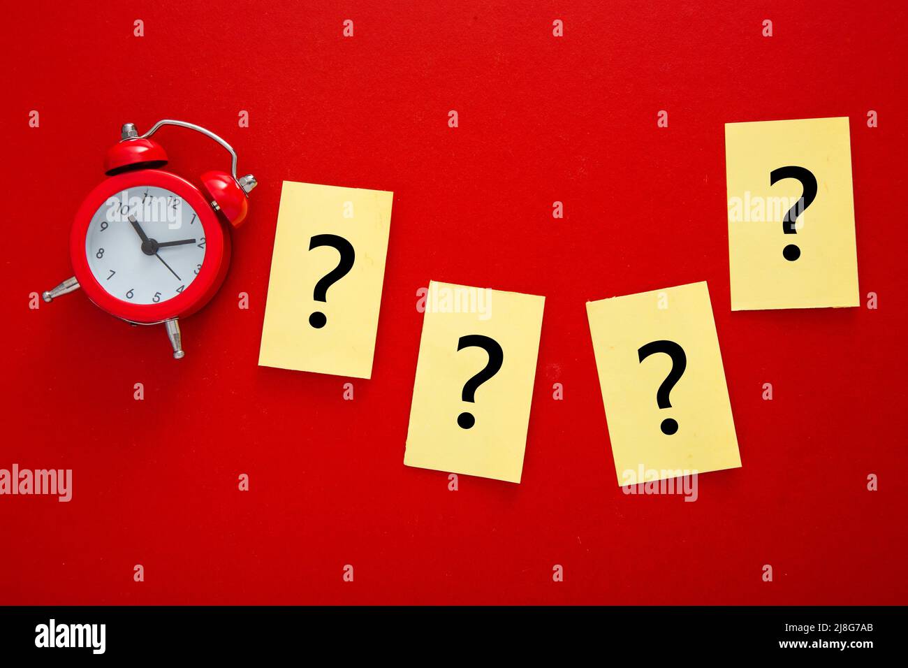 a question mark a red alarm clock . FAQ frequency asked questions