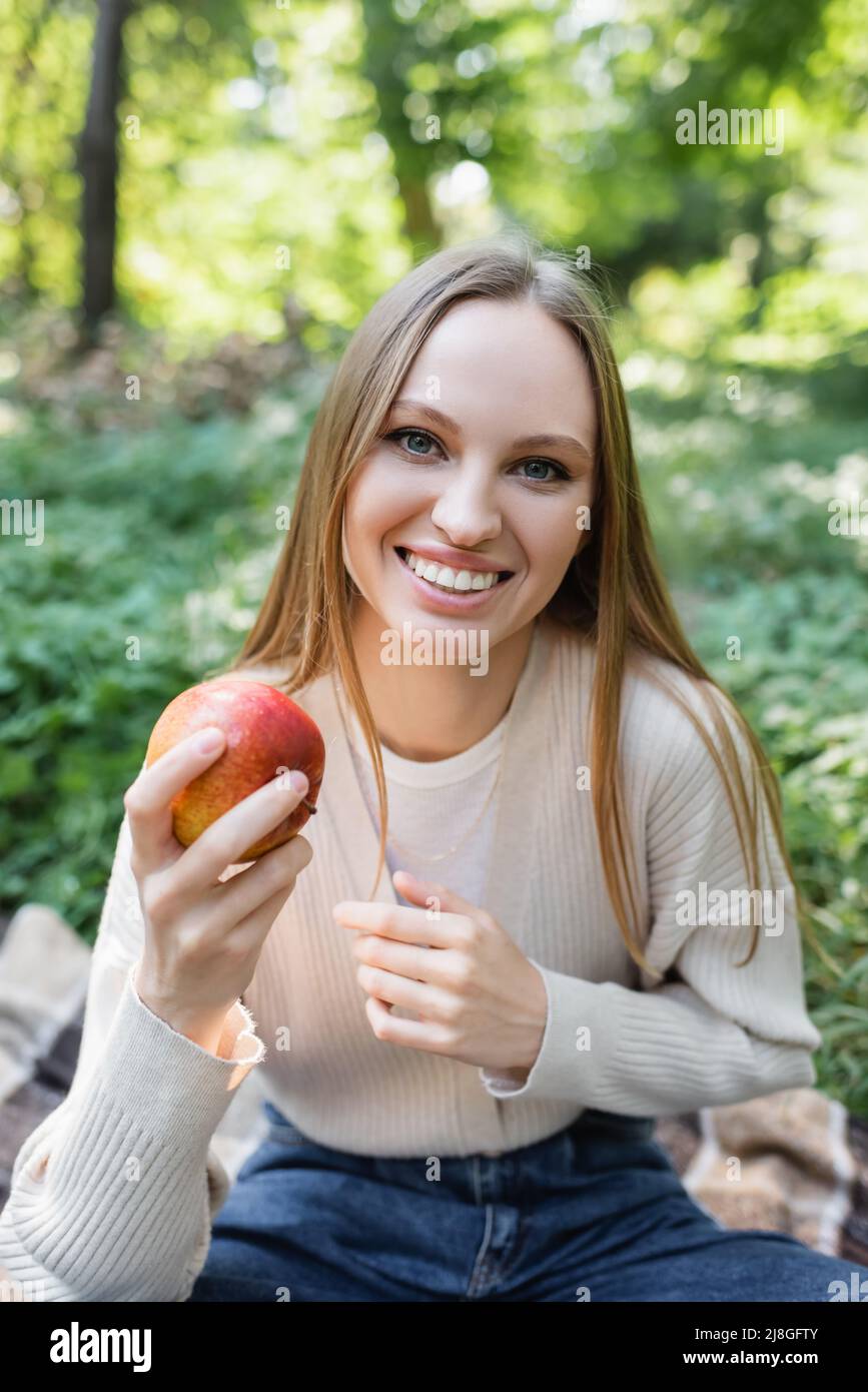 happy woman holding red tasty apple in green park Stock Photo