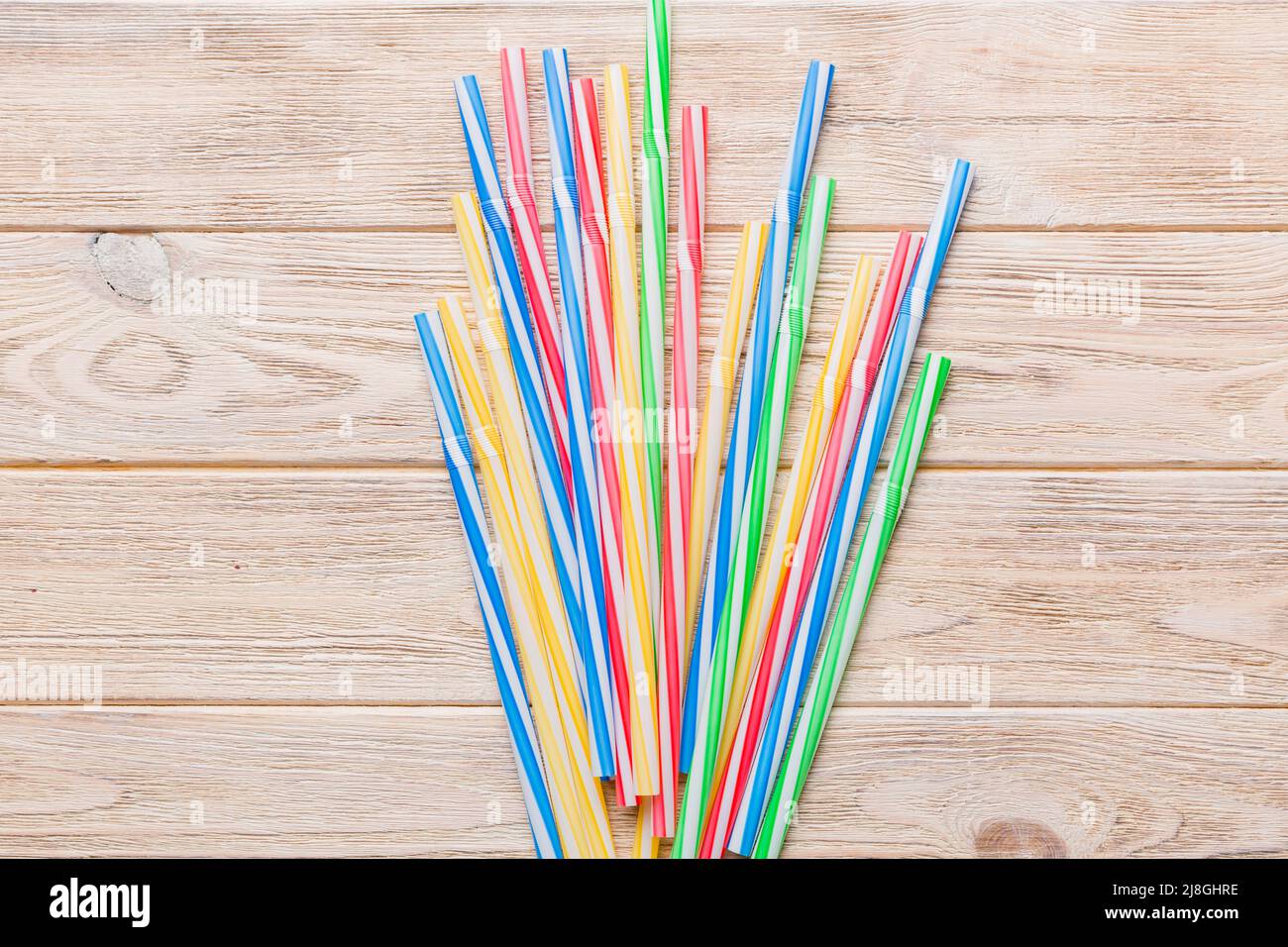 many multi-colored plastic tubes for cocktail on Colored background, top view. Stock Photo