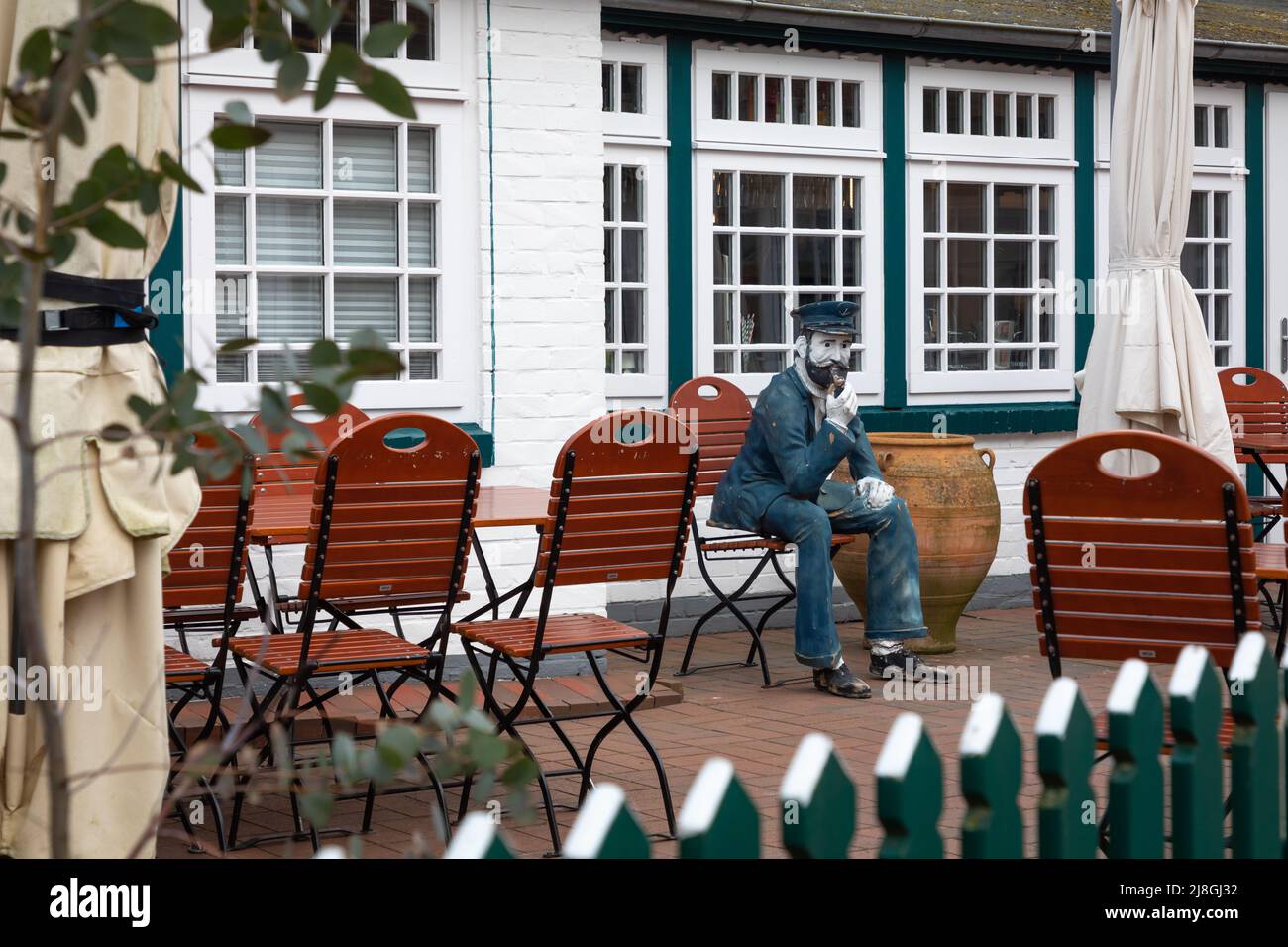 Sculpture of a mariner smoking pipe in front of a house, Spiekeroog, Germany Stock Photo