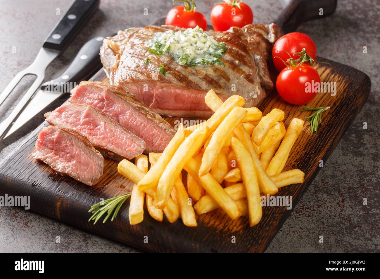 Medium Grilled Beef Steak with French Fries closeup on the wooden board on the table. Horizontal Stock Photo