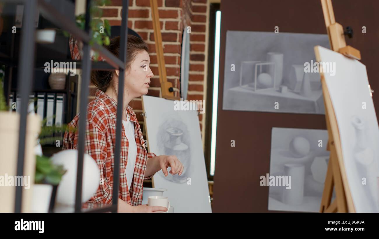 Female artist using vase model to explain drawing technique, teaching ...