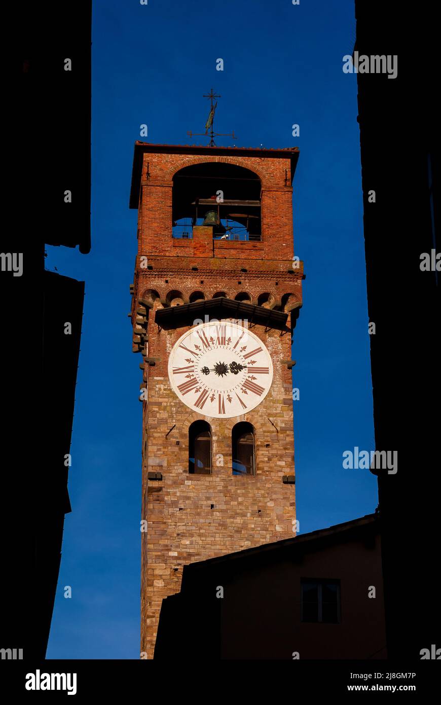 Lucca medieval 'Torre delle Ore', the city old clock tower rises among historical center buildings Stock Photo