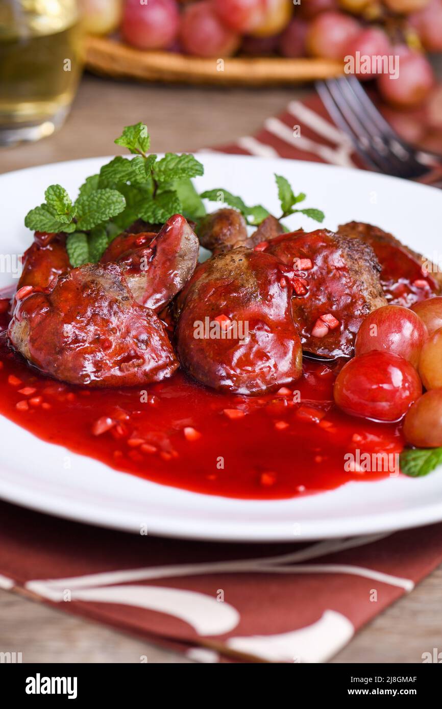 Warm salad with chicken liver and grapes on the plate. Warm salad from