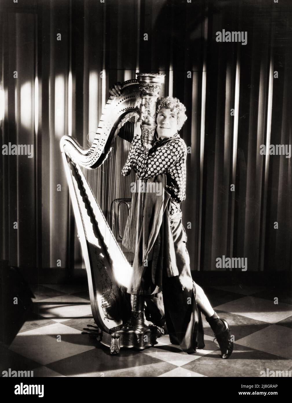 A publicity photo of Harpo Marx hugging his harp. Undated
