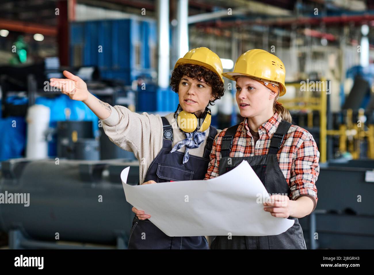 Young confident female engineer pointing at new equipment at meeting ...