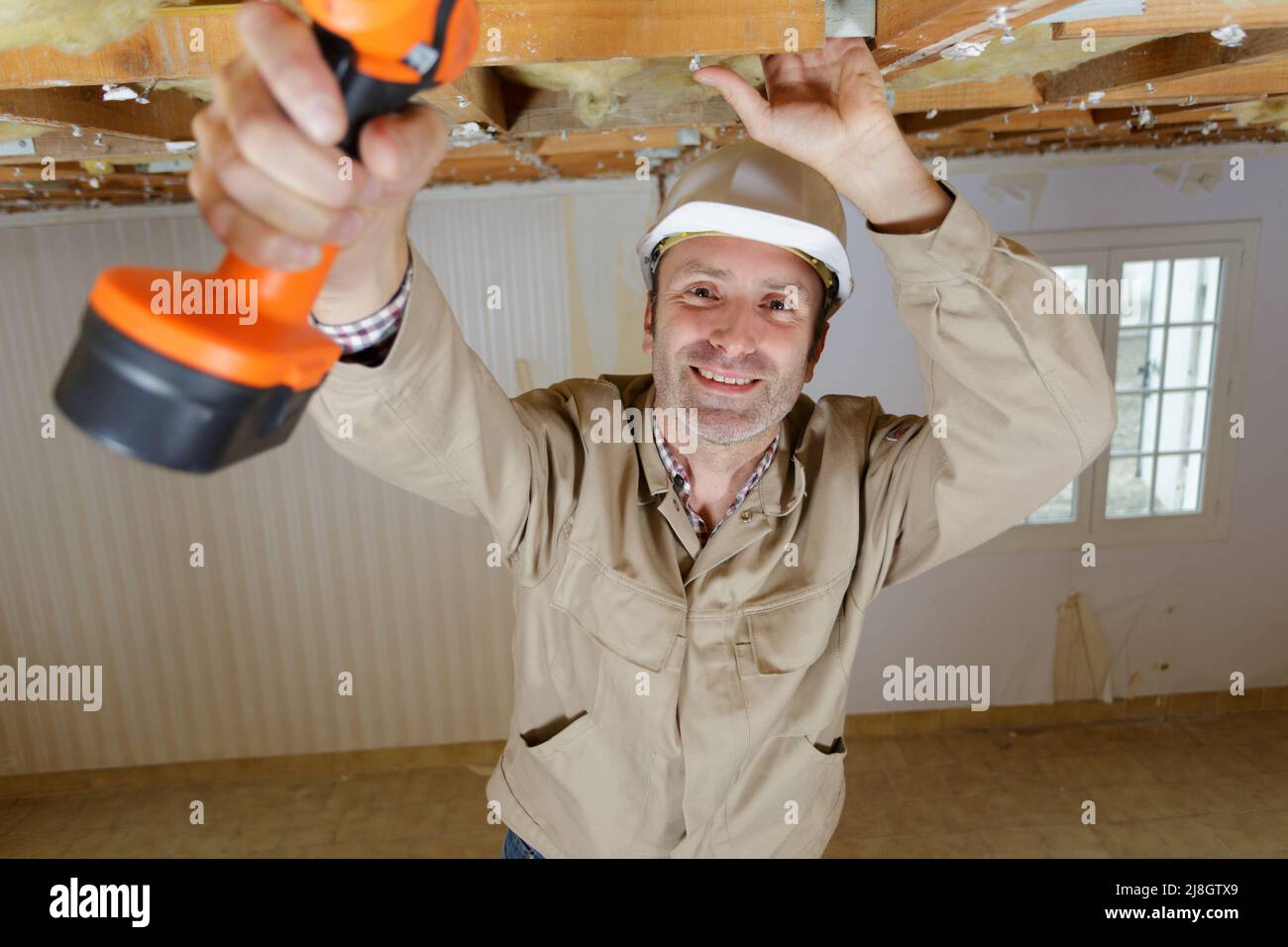 manual worker drilling ceiling with a drilling machine Stock Photo