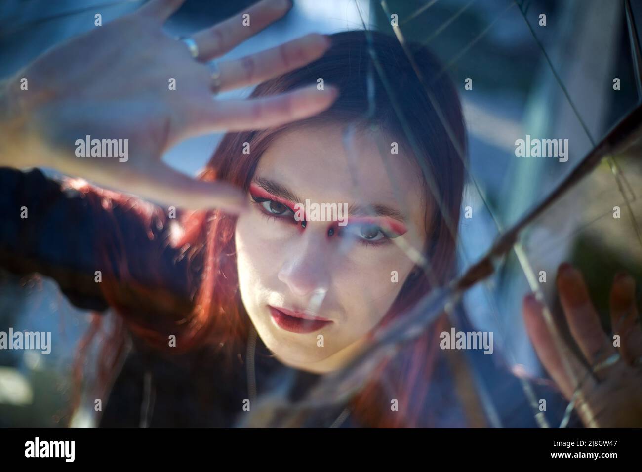 Excited woman indoors desperately looking through broken glass, danger and hopeless incident people in a trap Stock Photo