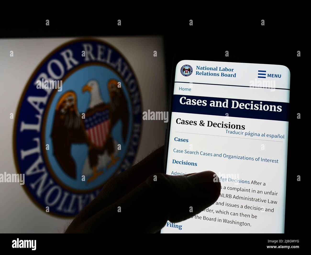 Person holding cellphone with webpage of US National Labor Relations Board (NLRB) on screen in front of logo. Focus on center of phone display. Stock Photo