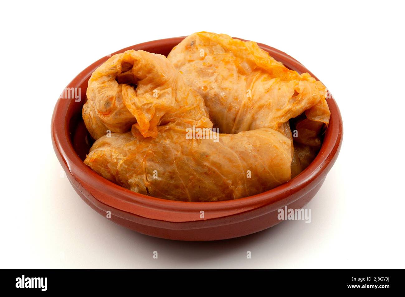 Traditional Balkan food recipe concept with cabbage rolls stuffed  with meat (Turkish:Sarma, Romanian: Sarmale) in brown pottery bowl isolated on whit Stock Photo
