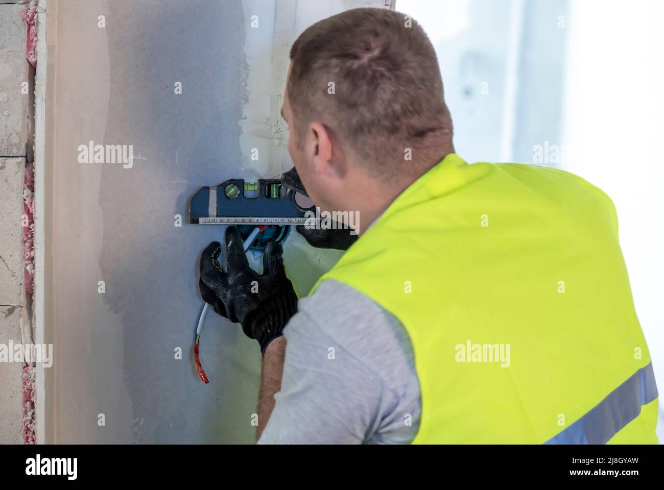 Installation of electrical outlets. An electrician with a level inserts