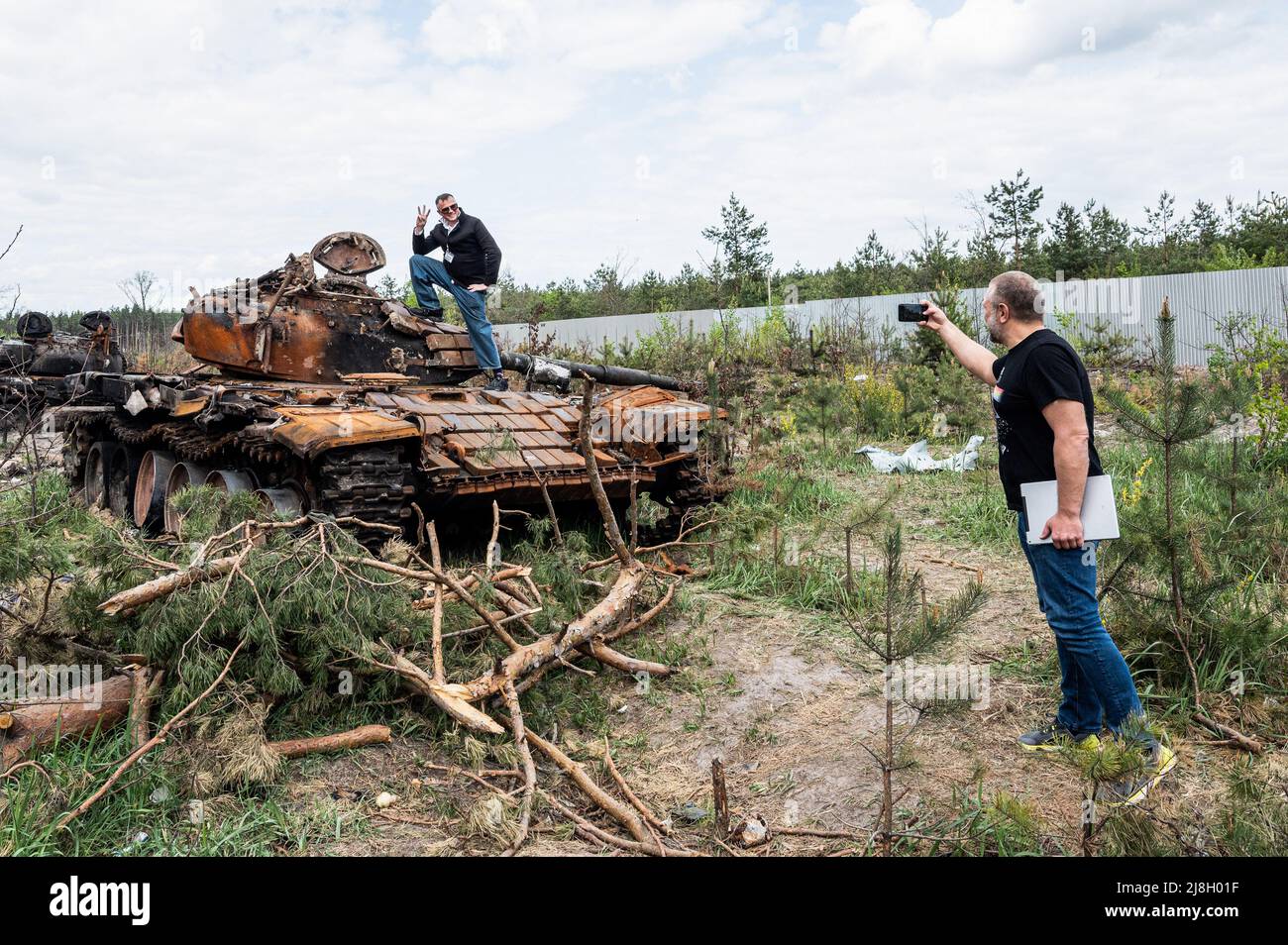 Nalyvaikivka, Ukraine. 15th May, 2022. A man being photographed in front of a destroyed Russian tank in Nalyvaikivka. Credit: SOPA Images Limited/Alamy Live News Stock Photo