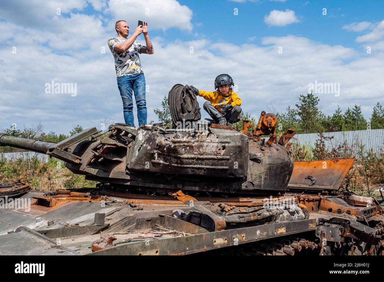 Nalyvaikivka, Ukraine. 15th May, 2022. A man taking a photograph and a child sitting on a destroyed Russian tank in Nalyvaikivka. Credit: SOPA Images Limited/Alamy Live News Stock Photo