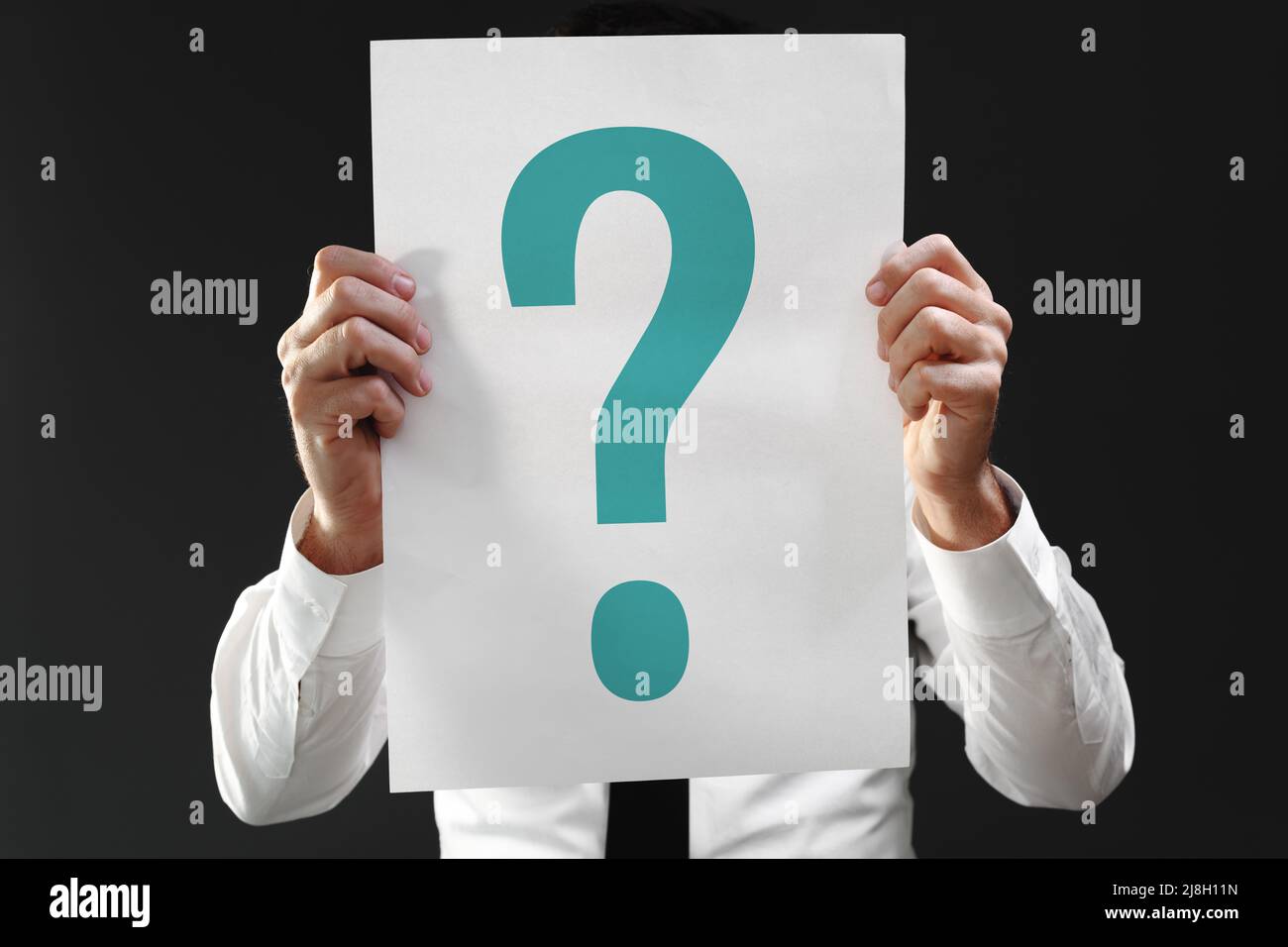 Perplexed businessman holding paper with question mark printed, selective focus Stock Photo
