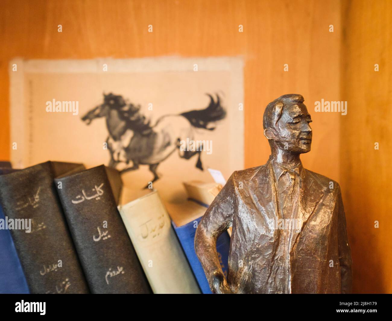 A small, bronze sculpture of Gulom on a bookcase in front of a horse drawing. At writer, poet, author, literary translator Garfur Gulom's home, house Stock Photo