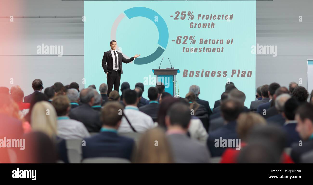 Businessman presenting a business plan at a conference with many people in the audience Stock Photo