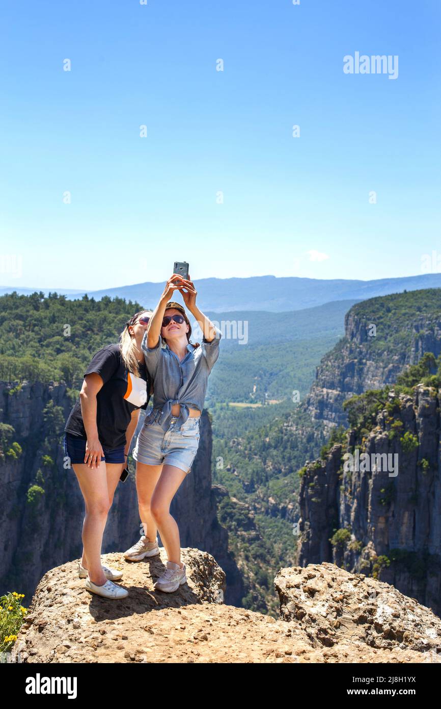 Tazi Canyon landscape in Manavgat Turkey. happy girls take selfies on the steep slope. valley and cliff Stock Photo
