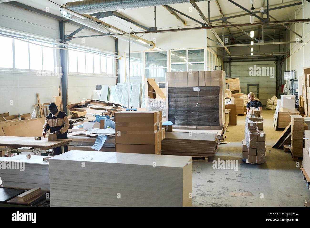 Manual workers working with freight in cardboard boxes at distribution warehouse for further export Stock Photo