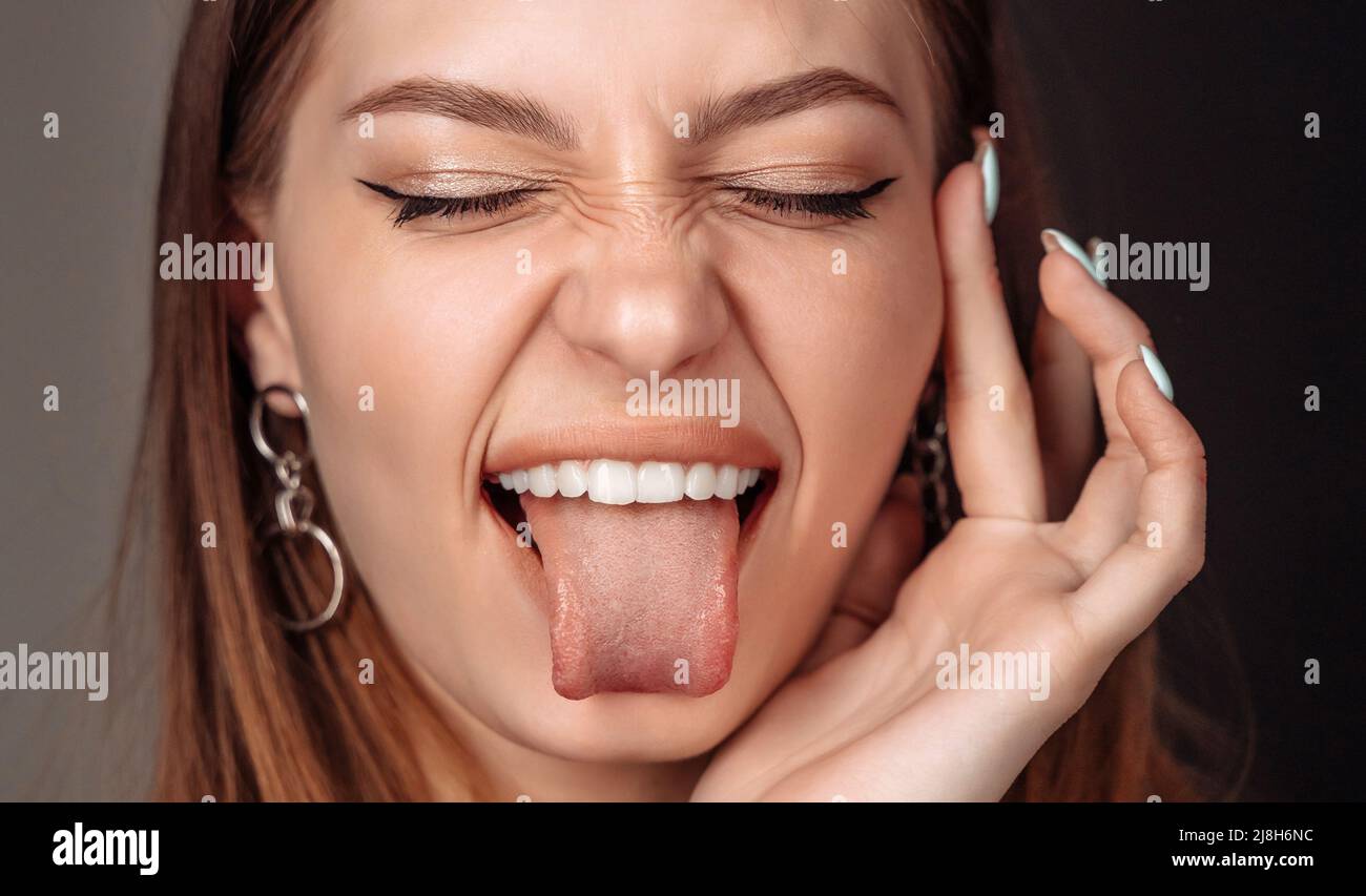 Girl laughs close-up of the face, woman show tongue, portrait with open mouth and protruding tongue.  Stock Photo