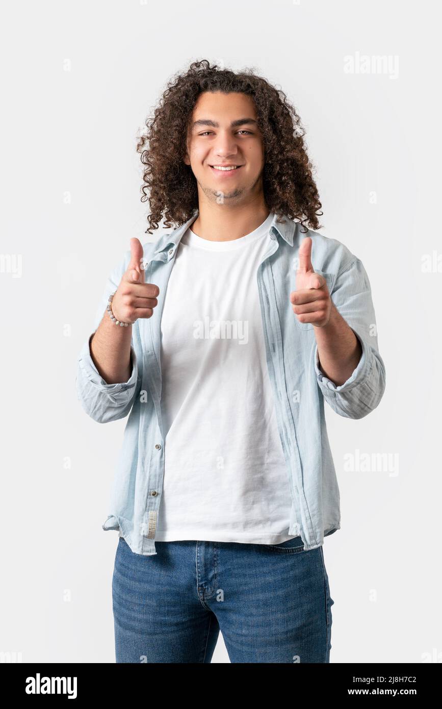 Close up of young good looking man with long and curly hair is pointing with his finger, isolated on white background. High quality photo Stock Photo
