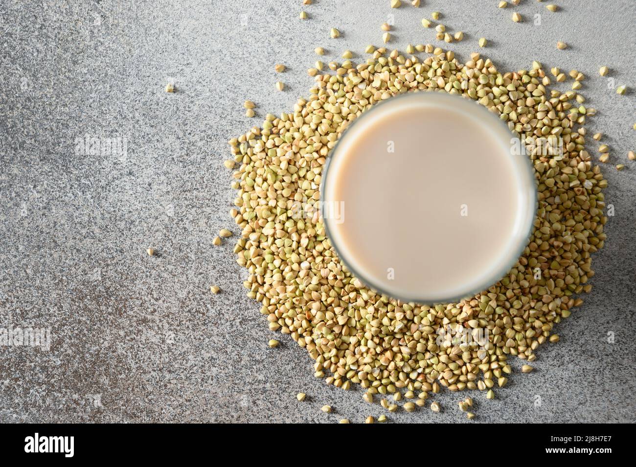 Green buckwheat milk in glass on gray background. View from above. Copy space. Dairy free. Stock Photo