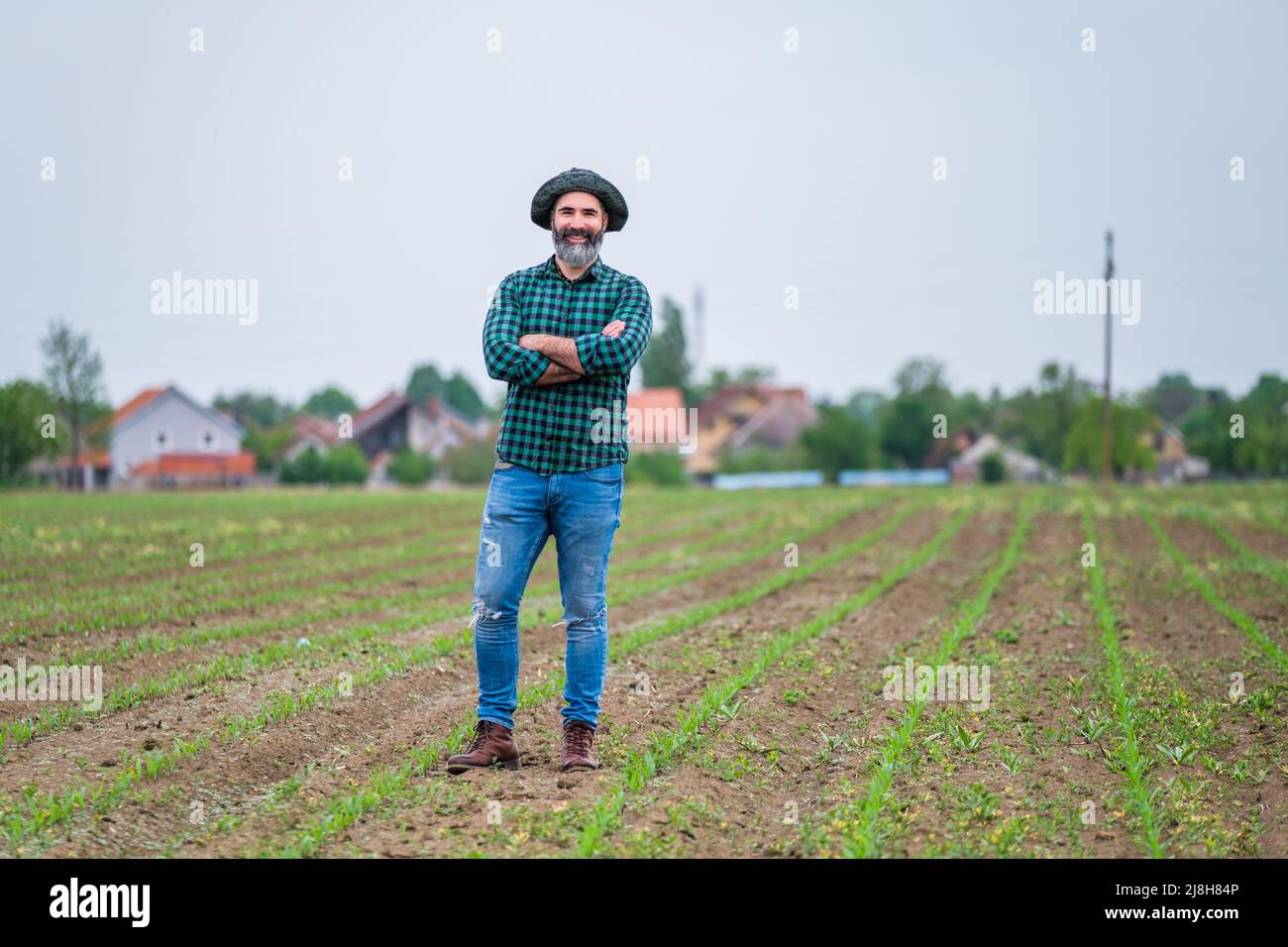 Happy farmer is standing in his growing corn field. Stock Photo