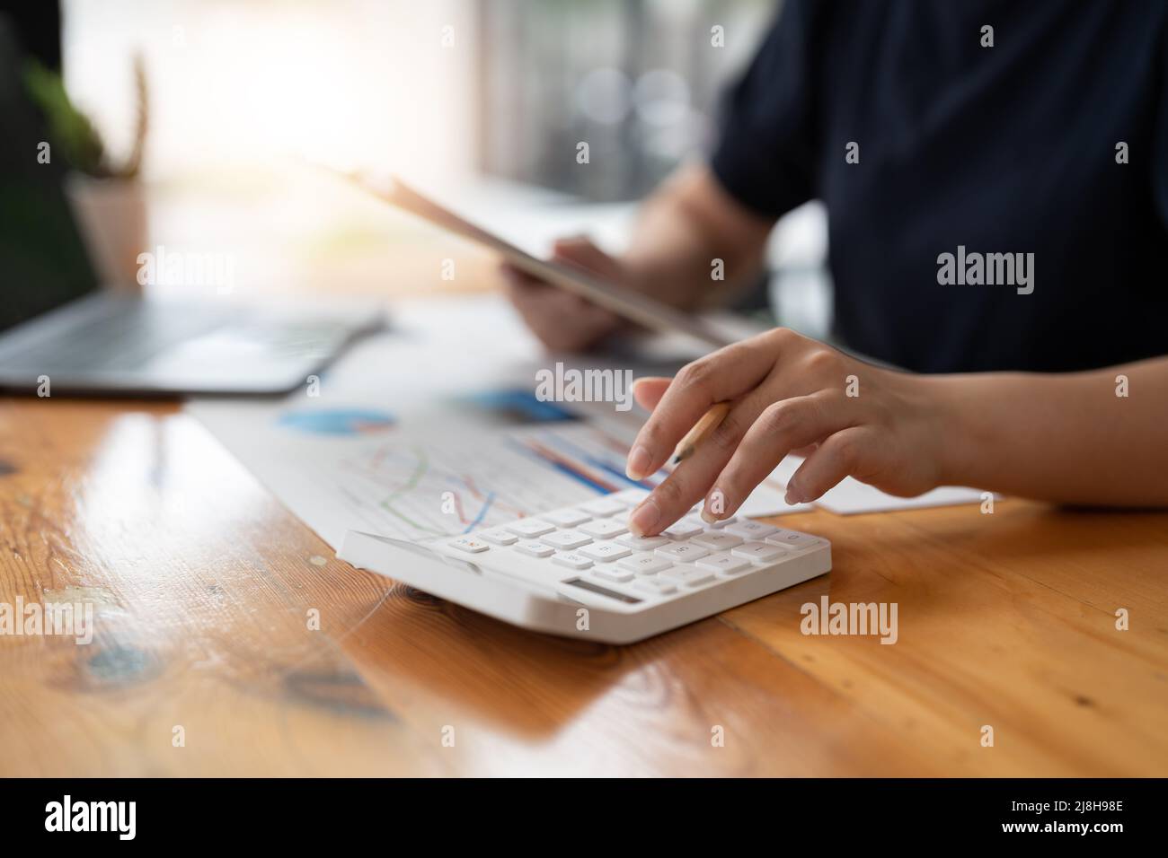 Accountant bookkeeper woman using calculator and laptop for do math finance on wooden desk in office and business working background, tax, accounting Stock Photo