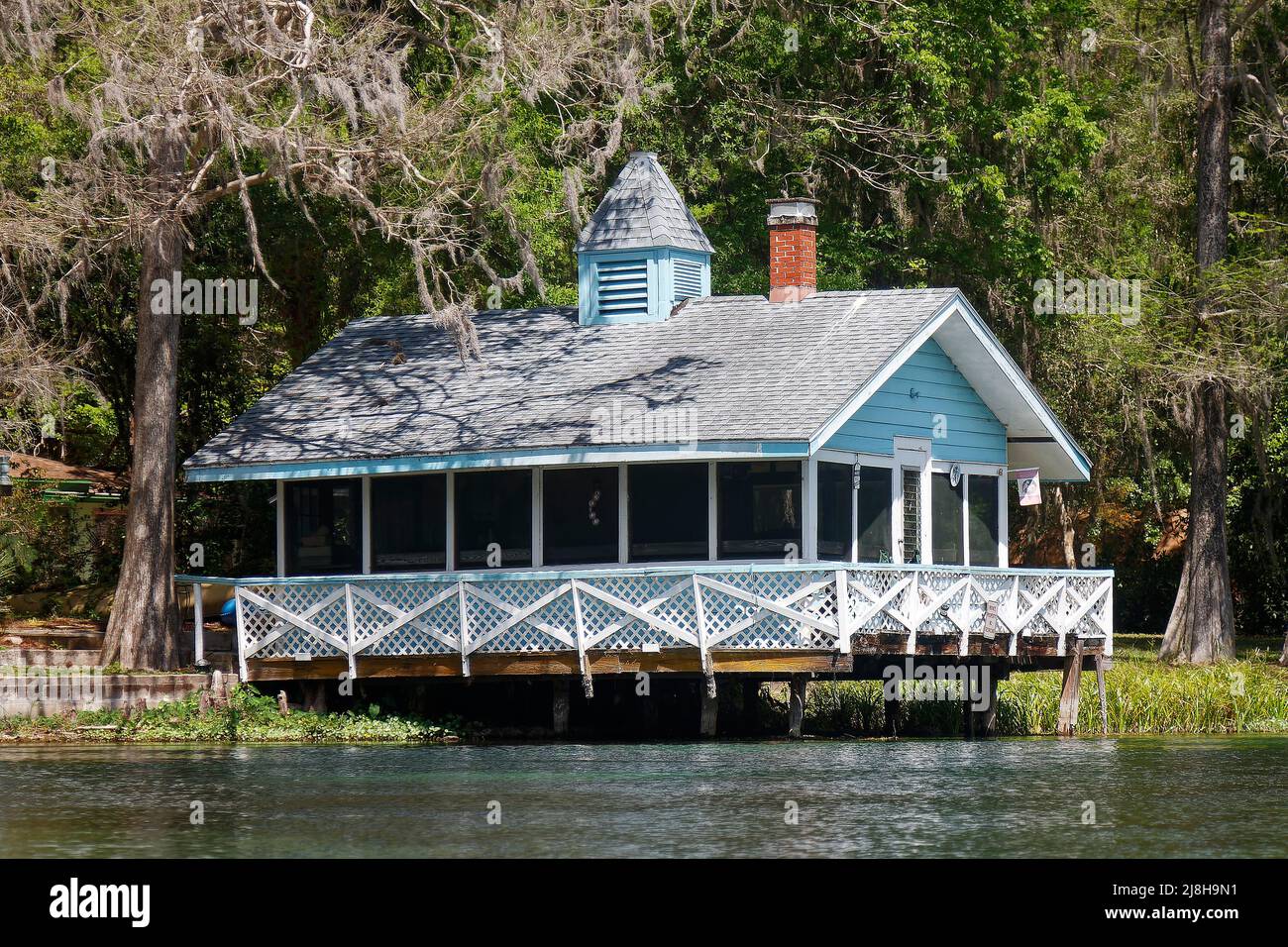 old wood building, on pilings over water, deck, lattice railing, brick chimney, cupola, Rainbow River, Florida, Dunnellon, FL, spring Stock Photo