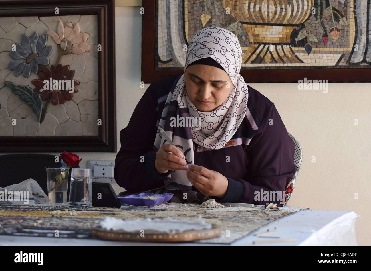 A Muslim lady wearing a hijab making mosaic art in Jordan at a charitable foundation where all the workers have a disability Stock Photo