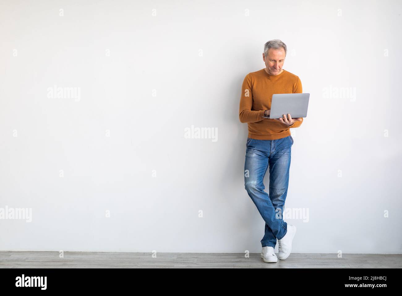 Confident mature man using laptop at home Stock Photo