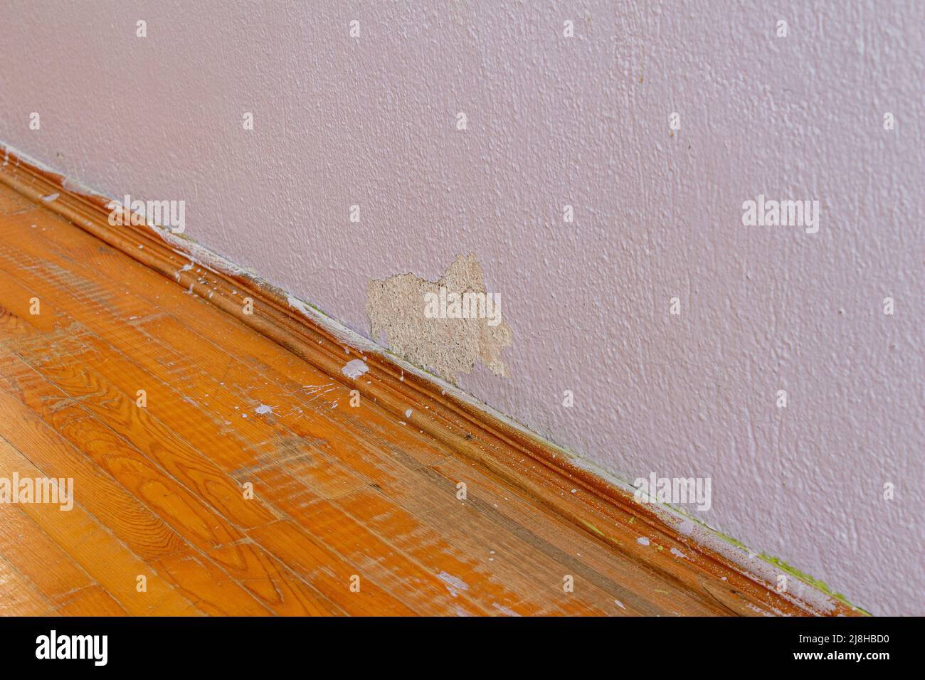 Old damaged concrete wall and parquet floor. Abandoned house with old weathered wall. Stock Photo