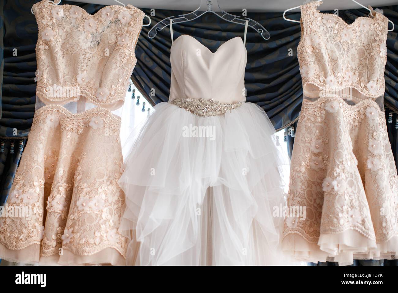 Wedding and bridesmaids dresses hanging by the window Stock Photo - Alamy