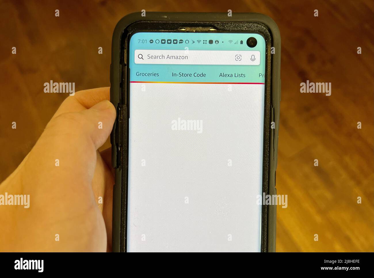 Person's hand holding a cellphone and viewing the Amazon Shopping app ...