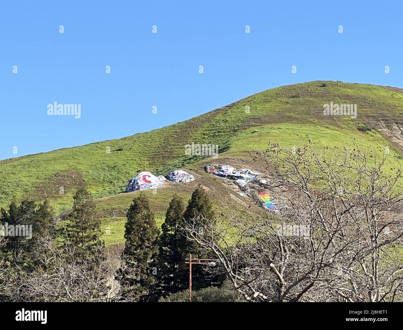 Painted rocks are visible on a hillside above Moraga, California, February 19, 2022. In a local tradition, people paint the rocks with slogans related to local sports games and other events. Photo courtesy Sftm. Stock Photo