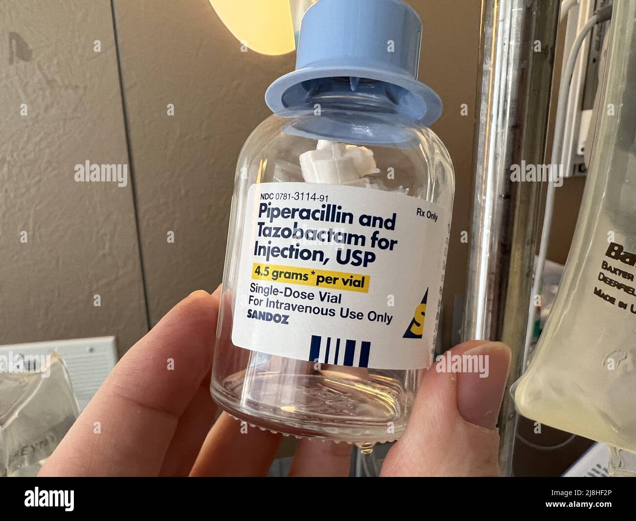Person's hand holding a vial of intravenous (IV) antibiotics from