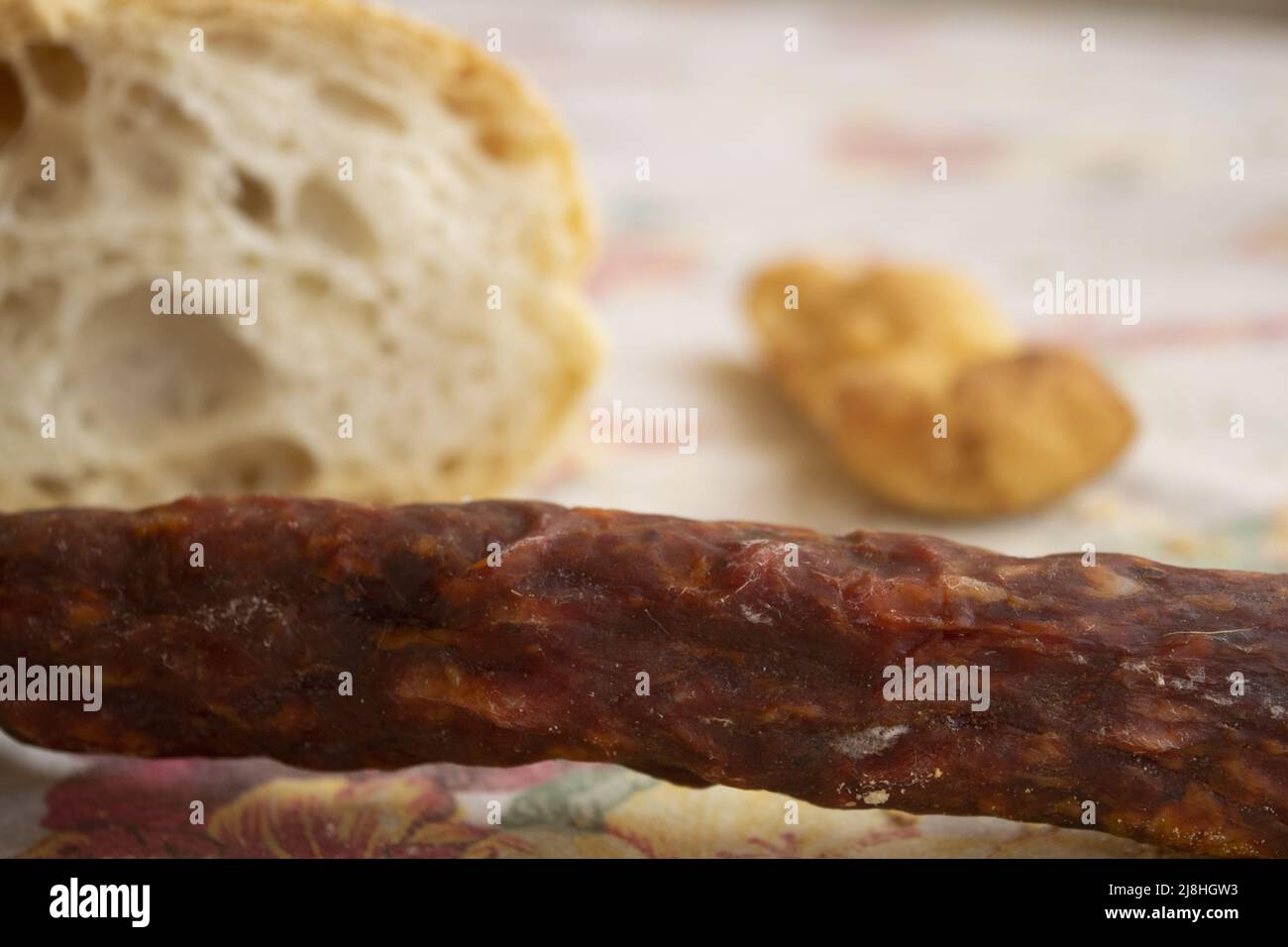 spicy salami with a loaf of bread and a bun on the background Stock