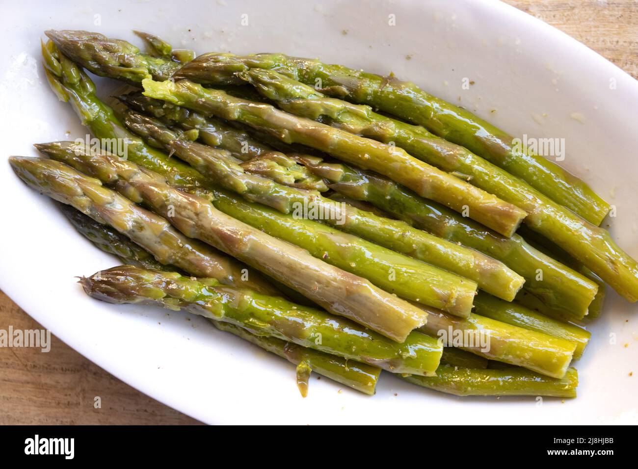 steamed asparagus in a serving dish dressed with oil and lemon Stock