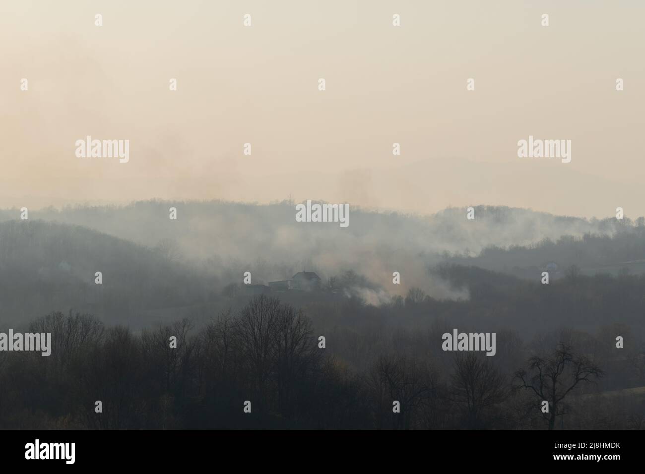 Forest fire in countryside, house in danger and smoky sky Stock Photo