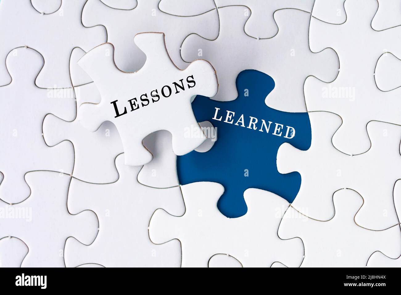 Lessons learned text on Jigsaw Puzzle over blue background. Stock Photo
