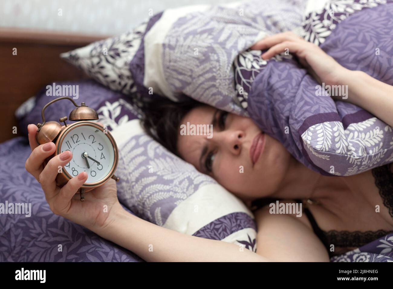 Adult woman wakes up with a headache, gets angry at the ringing alarm