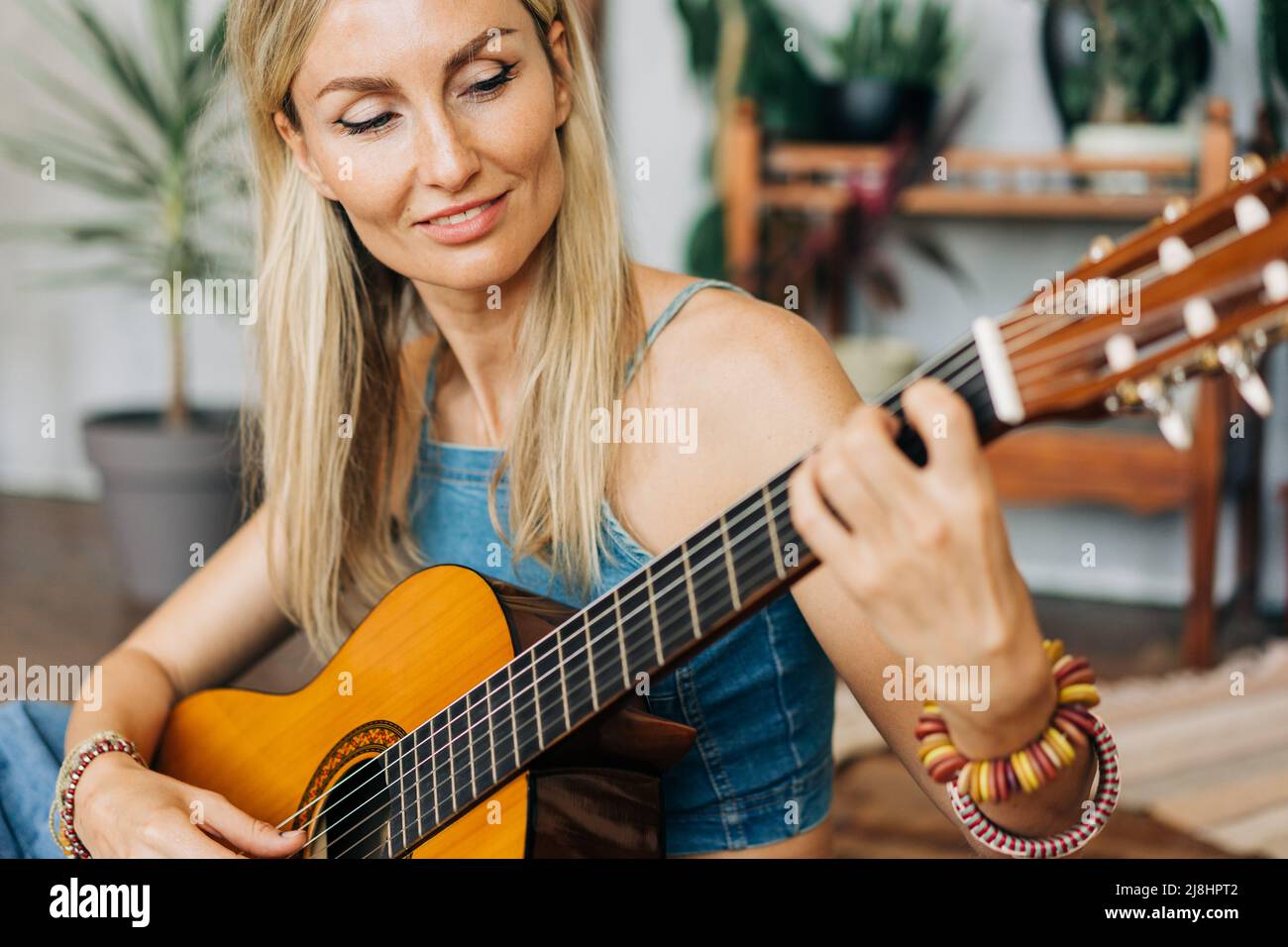 Close-up portrait of romantic blond young woman playing acoustic guitar ...