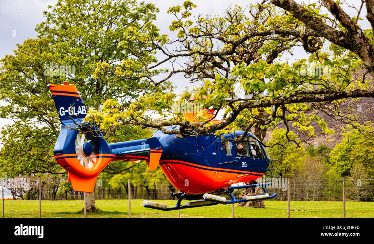 Blue and red G-GLAB - Airbus Helicopter H135 hovers in preparation   for take off, Applecross Peninsula  ,Bealach na Ba,  North Coast 500, Scotland Stock Photo
