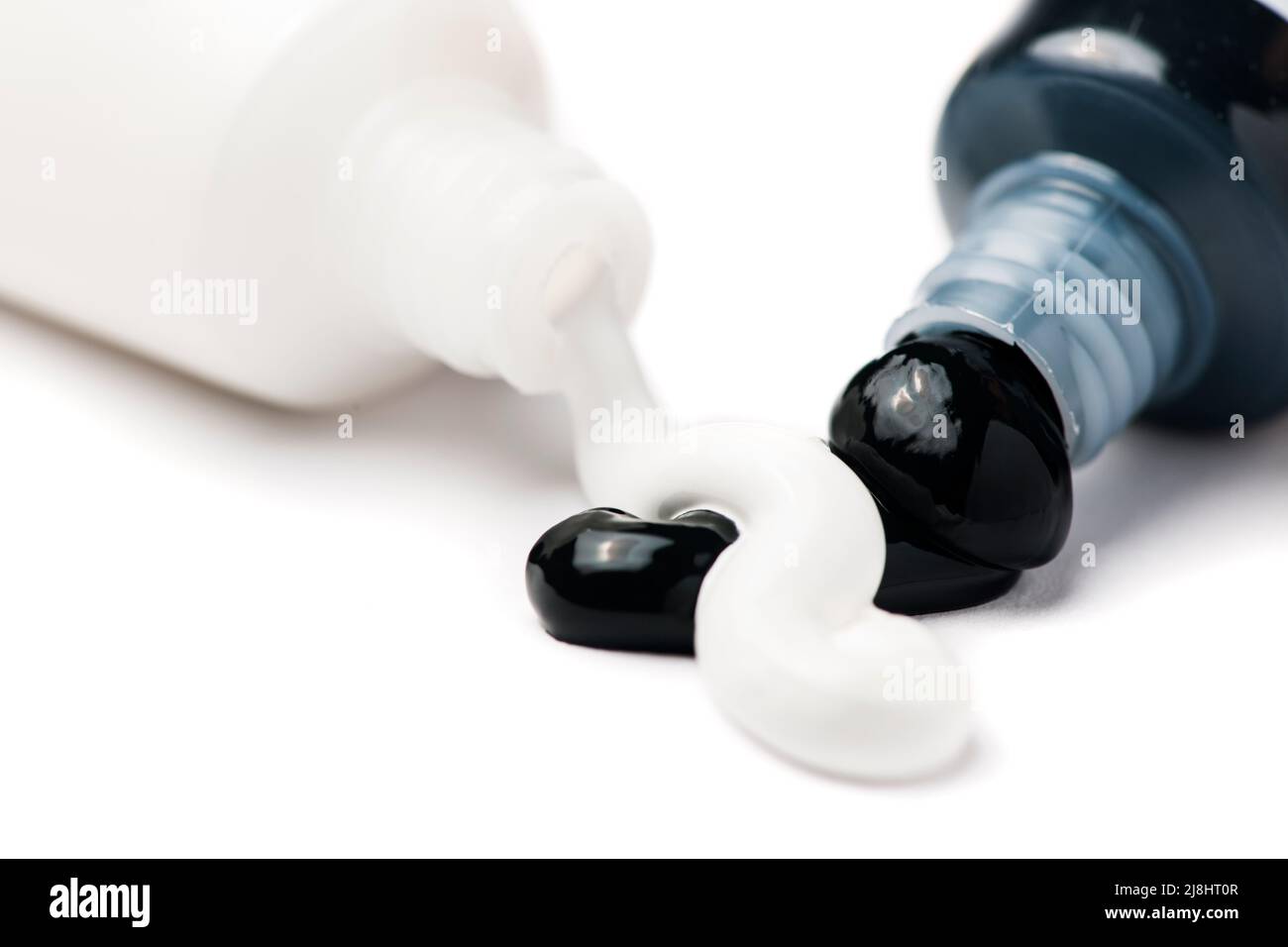 Close-up of two open tubes of artist paint with black and white acrylic paint pouring out on a white background. Stock Photo