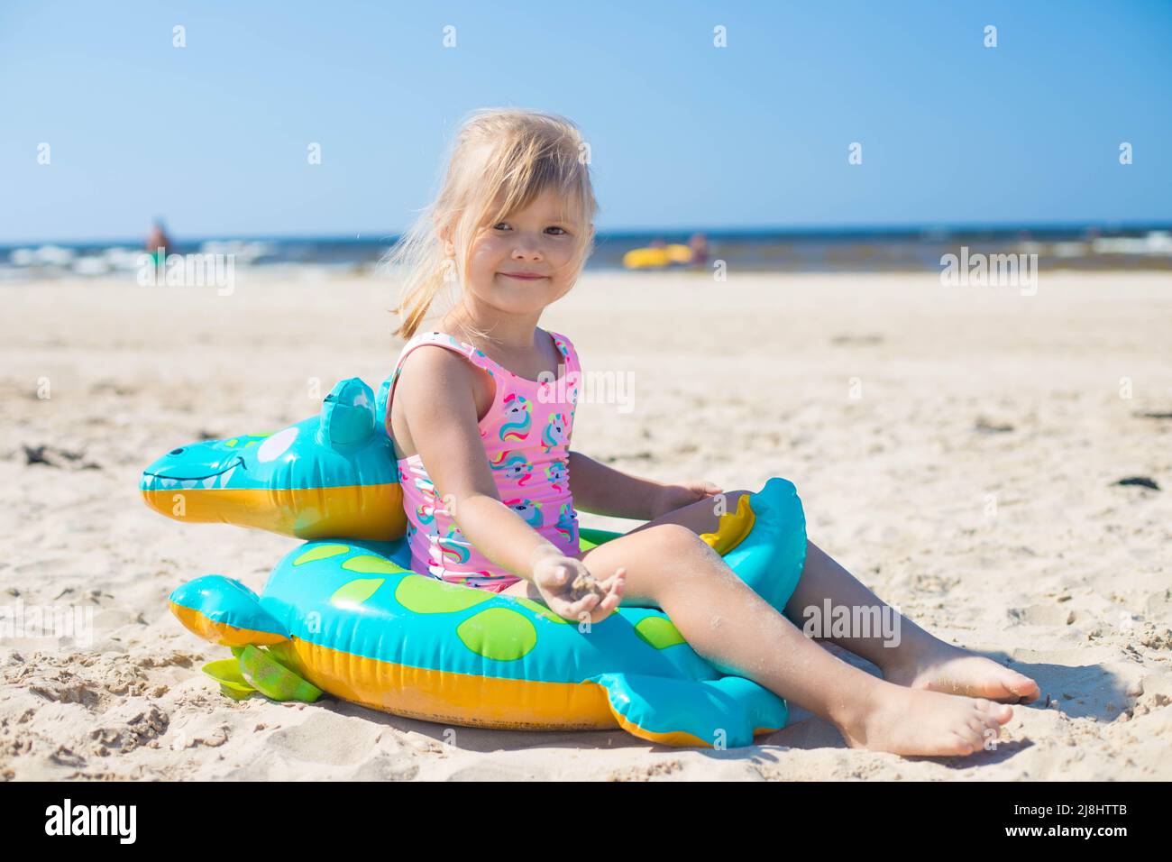 Happy girl sitting on an inflatable crocodile toy at the beach sunny