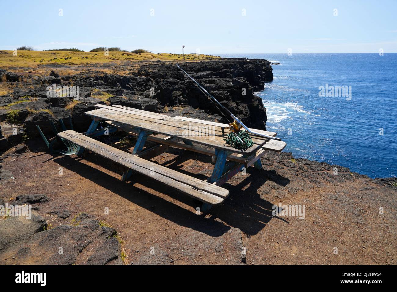 Picnic table with a fishing rod on the edge of a sea cliff in South