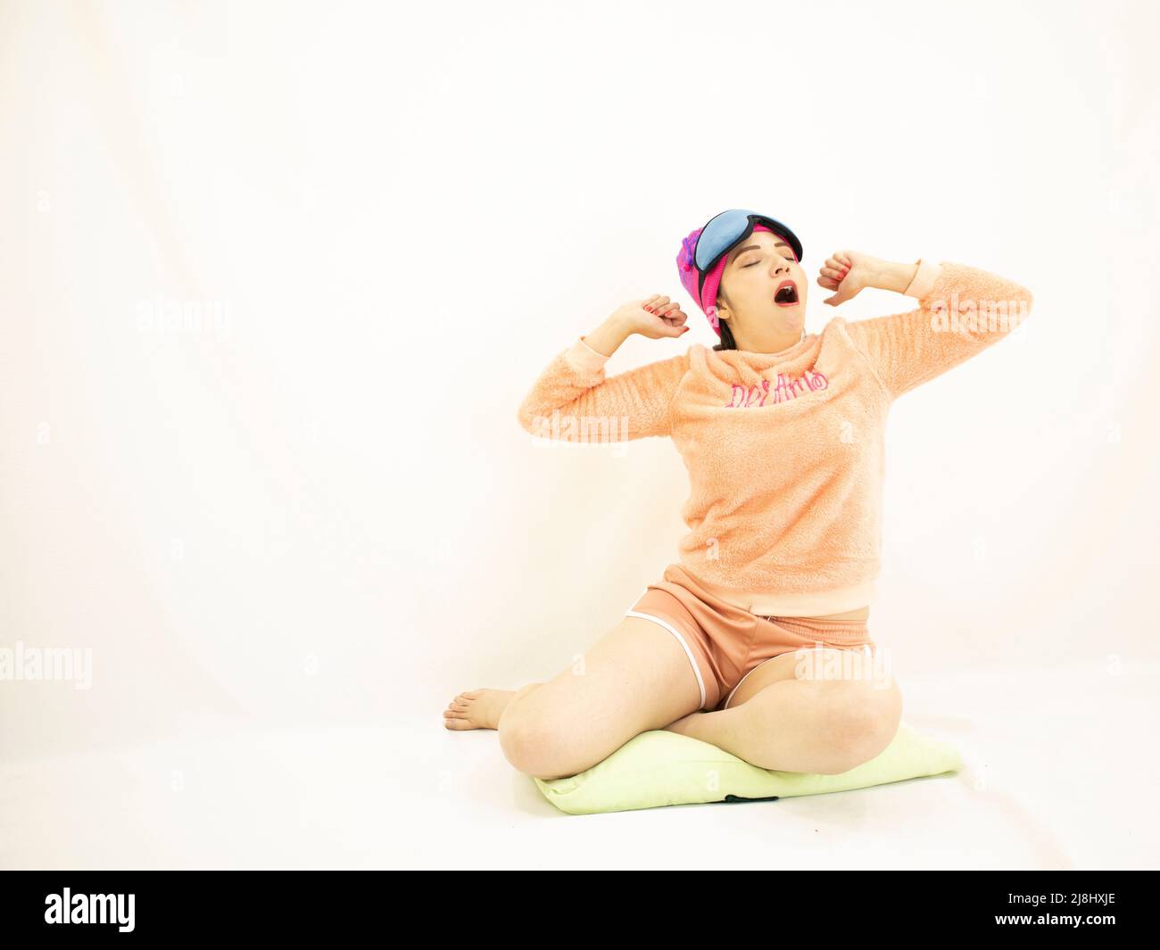 cute young asian white woman wearing a pink pajamas, yawning from sleep and tired, on white background Stock Photo