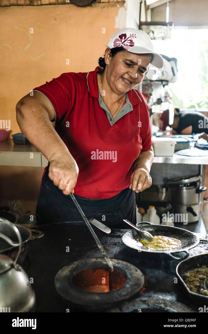 Woman cooks on a wood stove. Typical Costa Rican Restaurant. Stock Photo